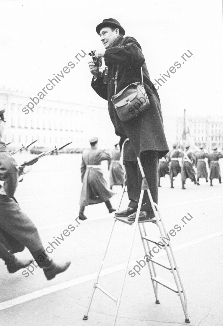 Фотокорреспондент газеты «Ленинградская правда» В.И.Логинов во время съемки военного парада на Дворцовой площади в день празднования годовщины Великой Октябрьской социалистической революции. 7 ноября [1960-е гг.]. Ленинград. Автор съемки Н.А.Науменков. ЦГАКФФД СПб. Ар 156431